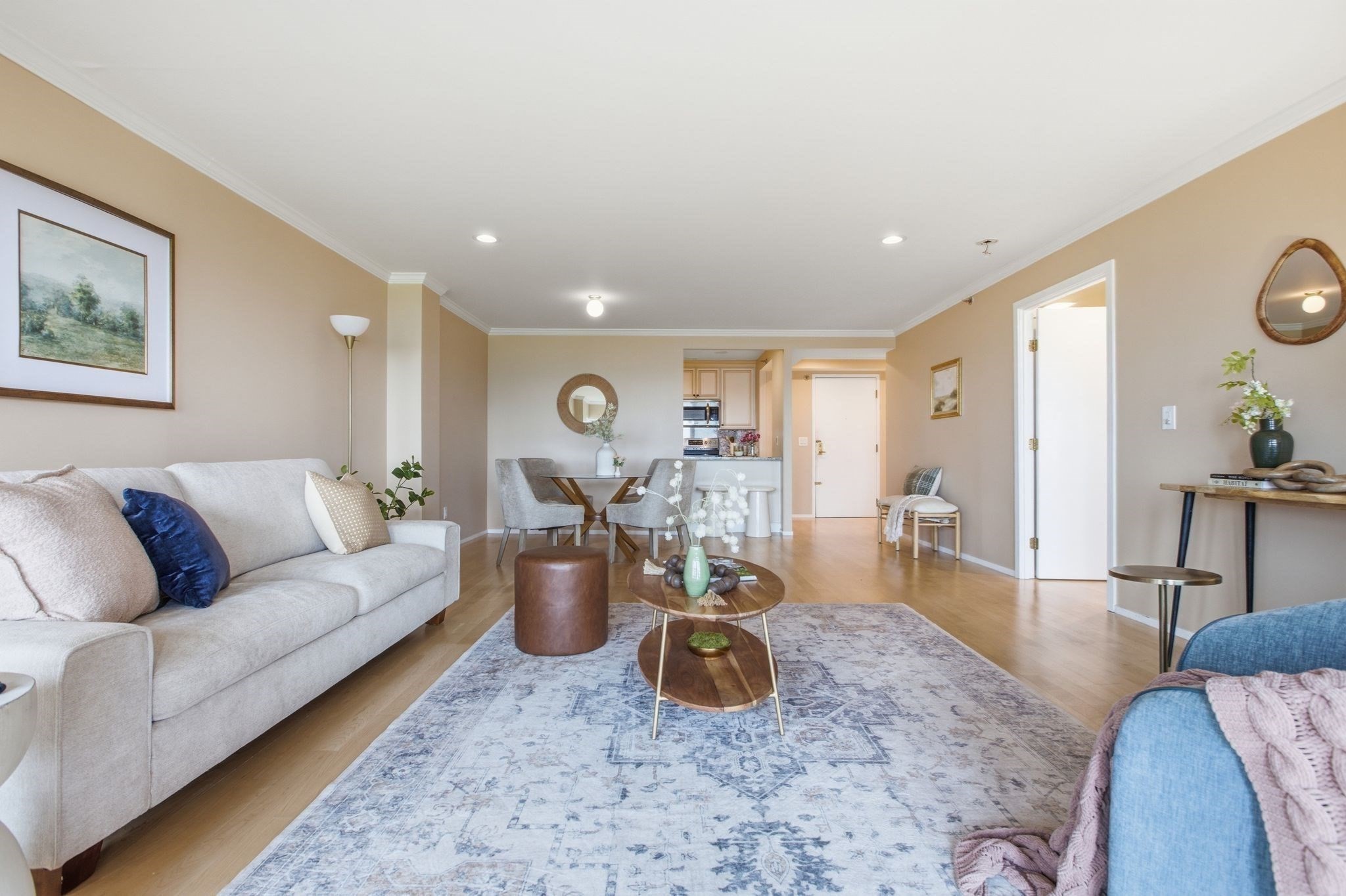Furnished living room with a patterned rug, gray sofa, and dining area opening to the kitchen.