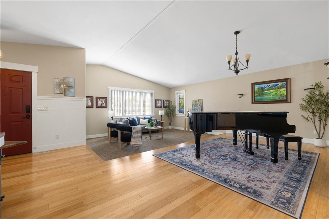 Living room with a black grand piano on a patterned rug and a seating area by the windows.