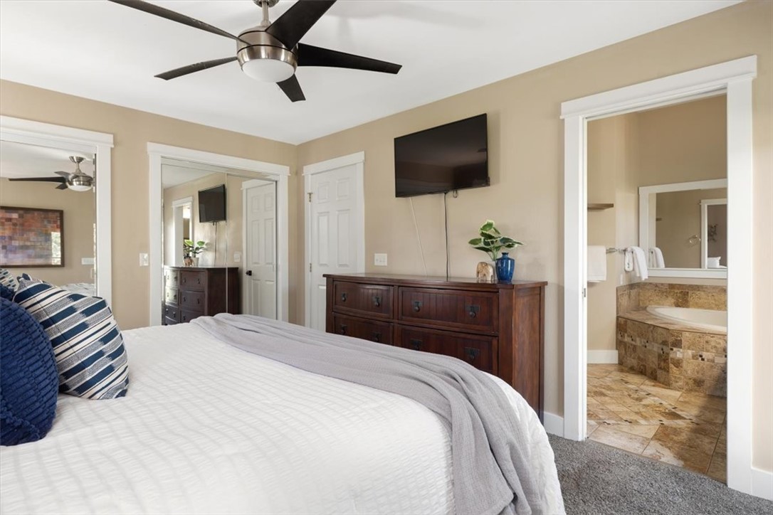 Bedroom with a white bed and blue pillows, opening to an ensuite bathroom with a tiled soaking tub.