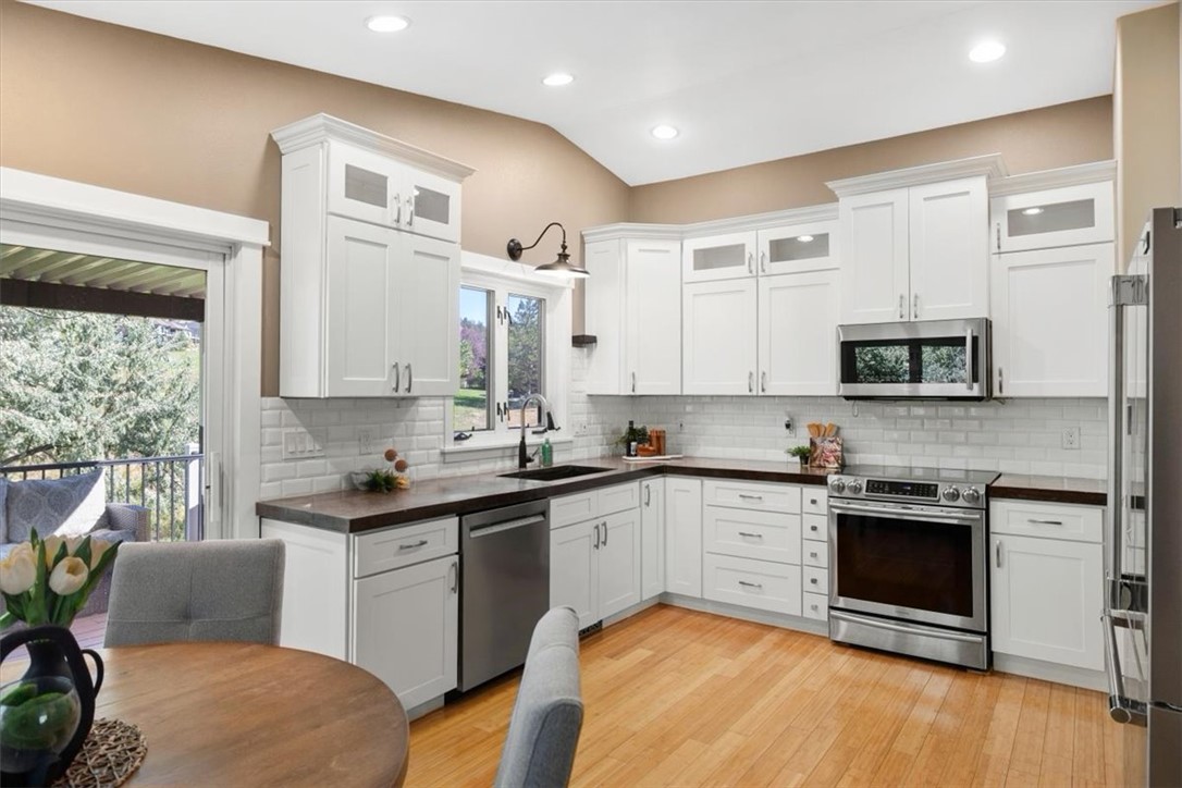 Kitchen with white cabinets, stainless steel appliances, hardwood floors, and a sliding door to a balcony.