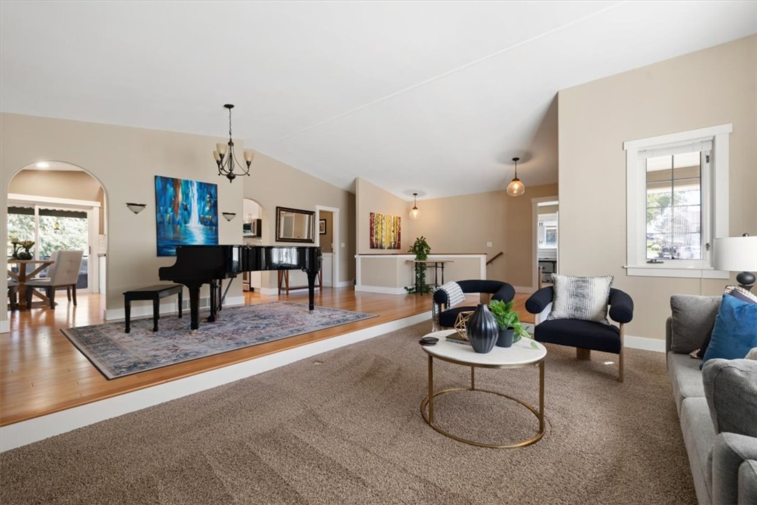 Living room with a black grand piano on a raised wood floor beside a carpeted seating area.