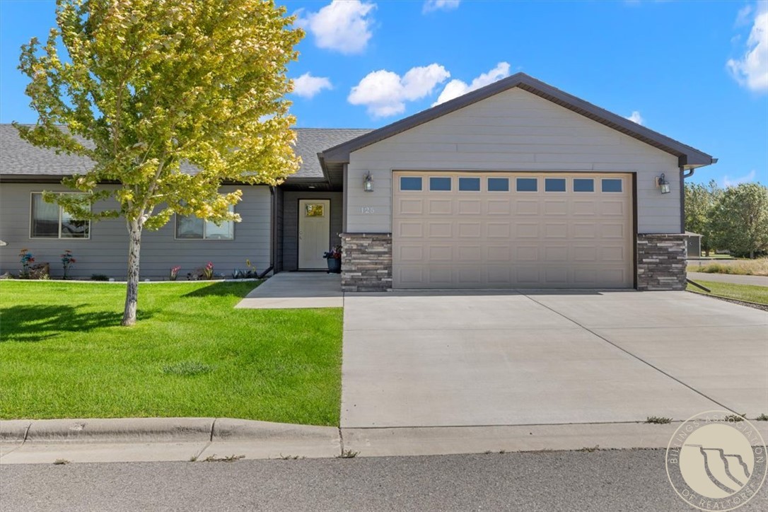 Gray single-story home with a two-car garage, stone accents, and a broad driveway.