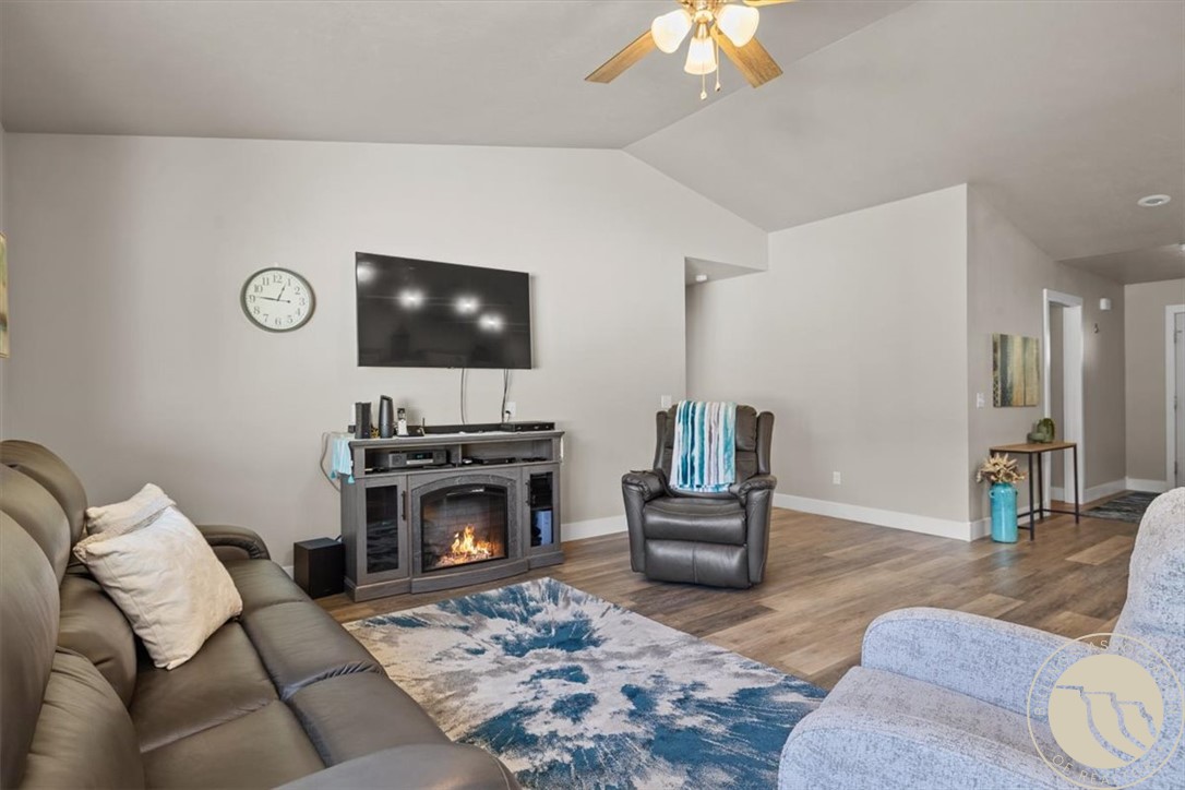Furnished living room with a vaulted ceiling, fireplace, and blue-and-white rug.
