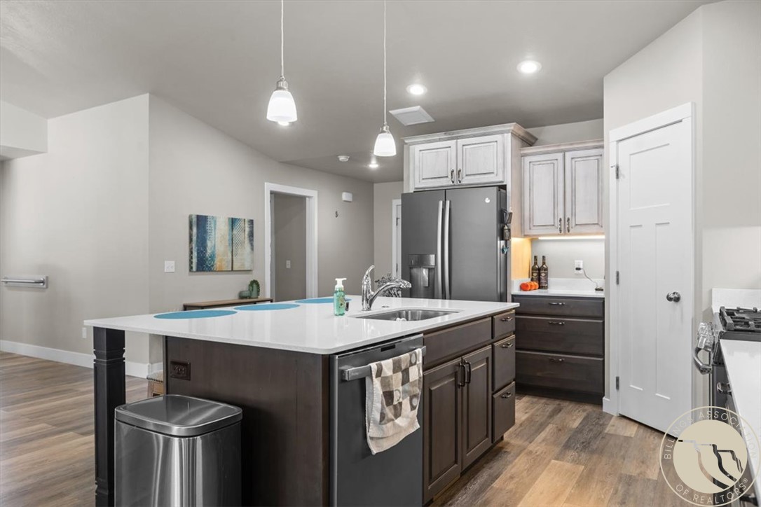 Kitchen with a large white island, dark cabinetry, and stainless steel appliances.