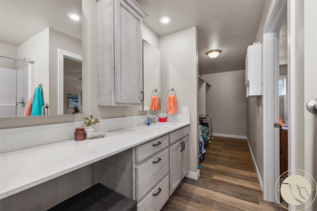Bathroom with a long double-sink vanity, gray cabinets, and a glass-enclosed shower.
