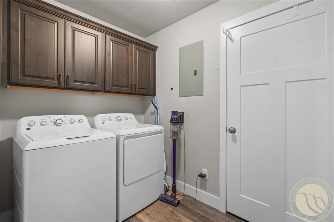 Laundry room with washer and dryer beneath dark wood cabinets.
