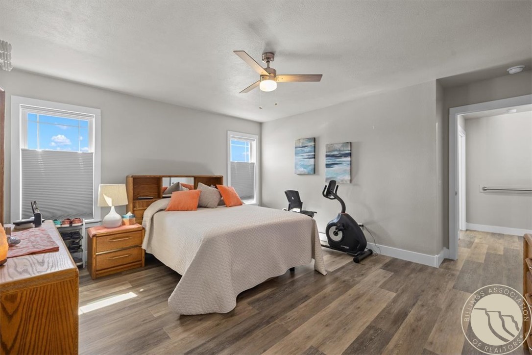 Bedroom with a large bed, two windows, ceiling fan, and exercise bike.
