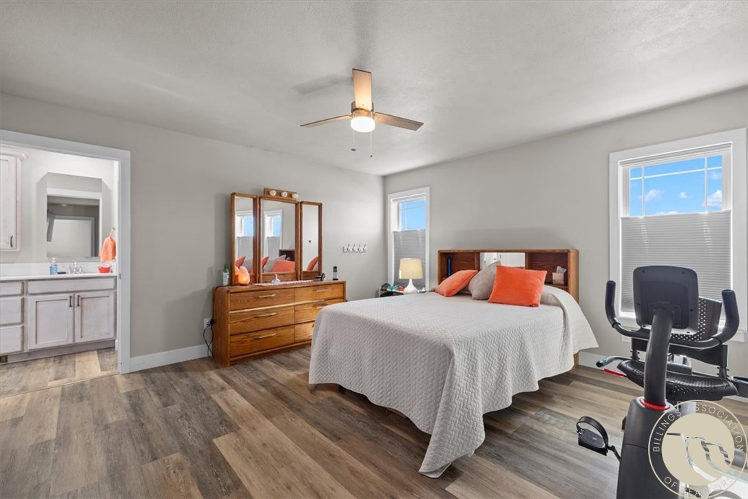 Furnished bedroom with a wooden bed, orange accent pillows, and an exercise bike beside the window.