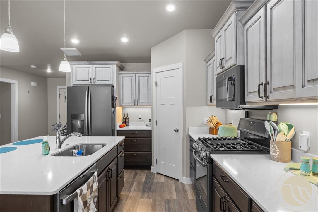 Kitchen with a large white sink island, stainless steel appliances, and two-tone cabinets.