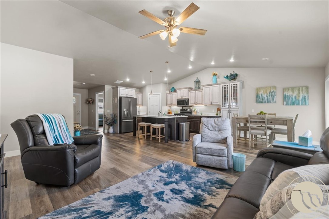 Open-plan living room with gray seating, blue rug, dining area, and kitchen island.