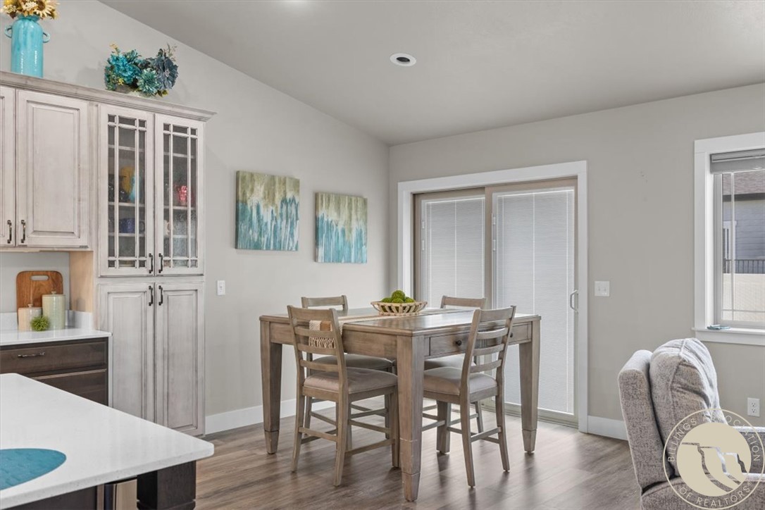 Dining area with a wooden table and chairs beside a sliding glass door.