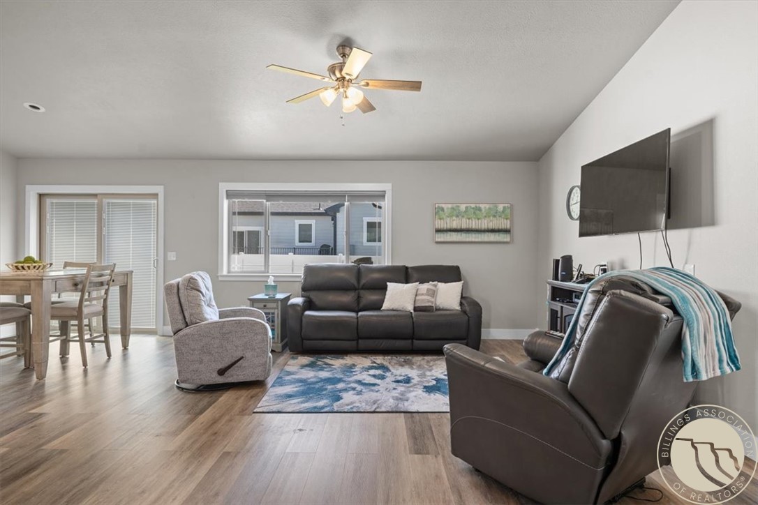 Furnished living room with dark leather seating, a blue area rug, and an adjoining dining area.