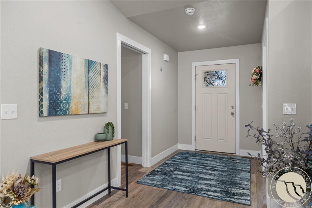 Home entryway with a stained-glass front door, blue rug, and narrow console table.