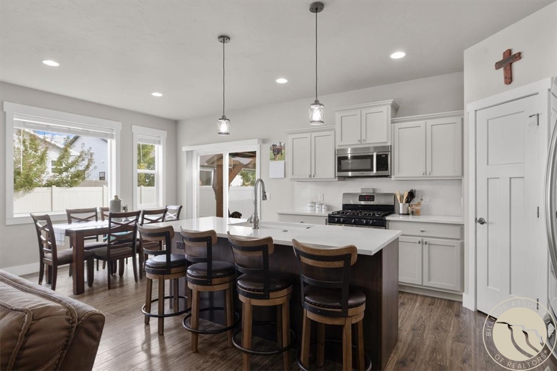 Kitchen with a large island, dark wood bar stools, white cabinetry, and an adjacent dining area.