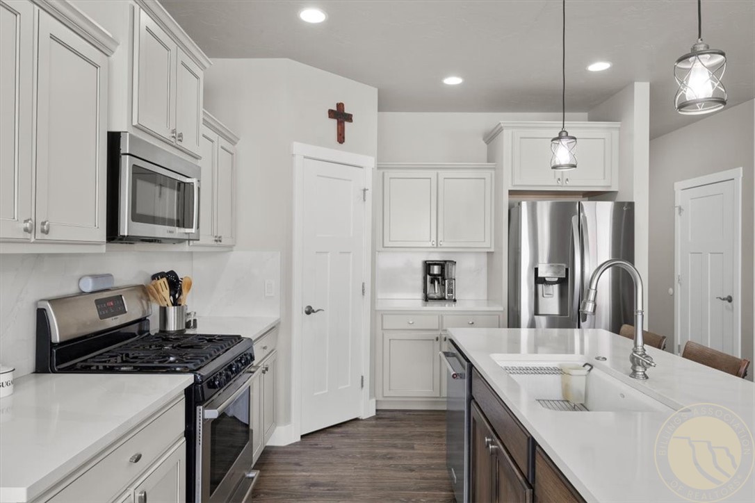 White kitchen with stainless steel appliances, gas range, and a large island with a double-basin sink.