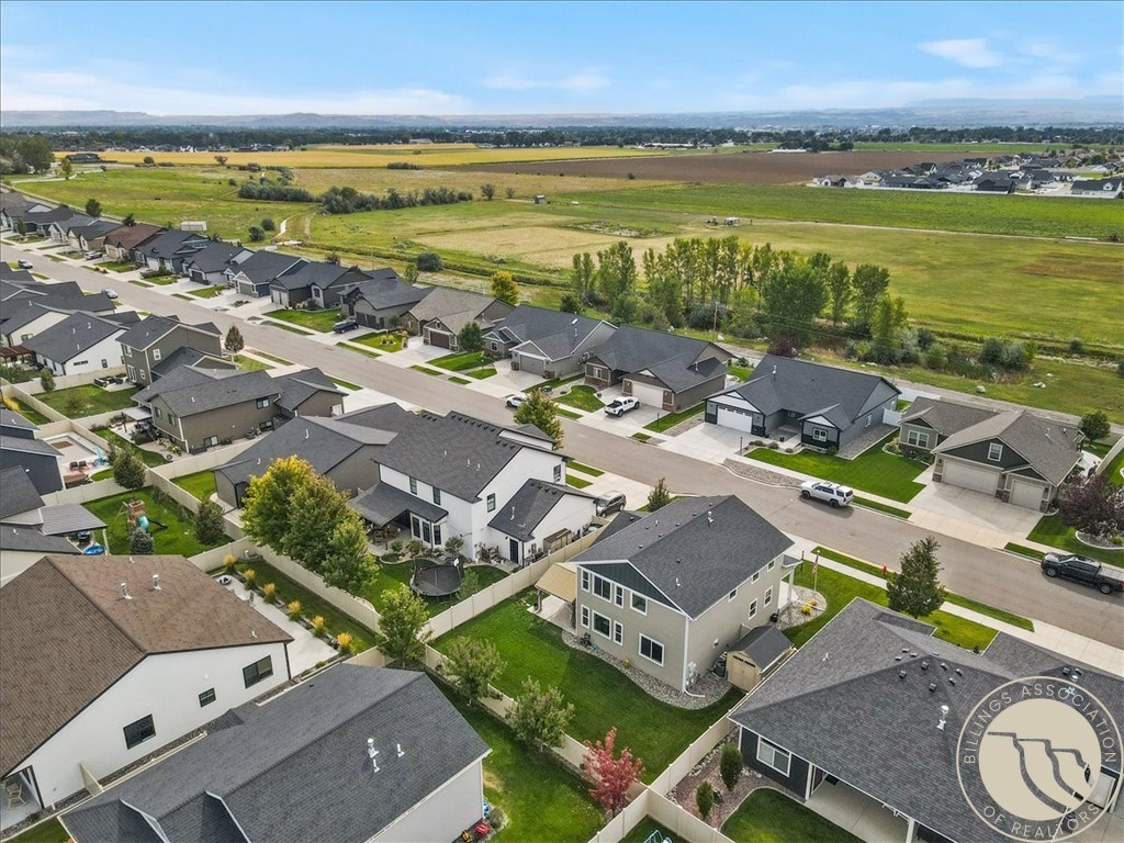 Aerial view of homes beside open fields, with distant hills on the horizon.