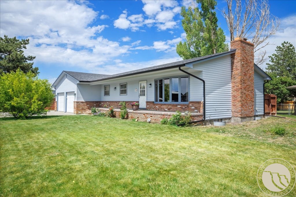 Single-story home with a tall brick chimney, attached garage, and broad green lawn.