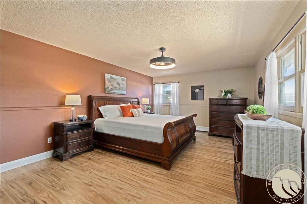 Furnished bedroom with a dark wood bed, terracotta accent wall, and large windows.