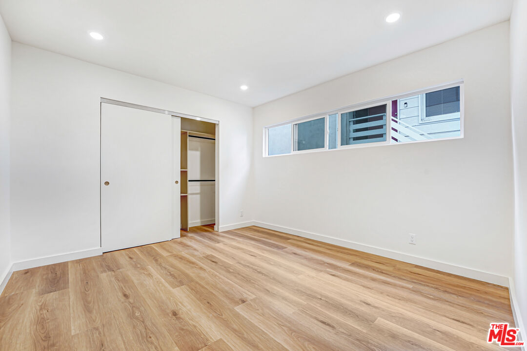 Vacant bedroom with light wood flooring, a partially open closet, and a narrow horizontal window.