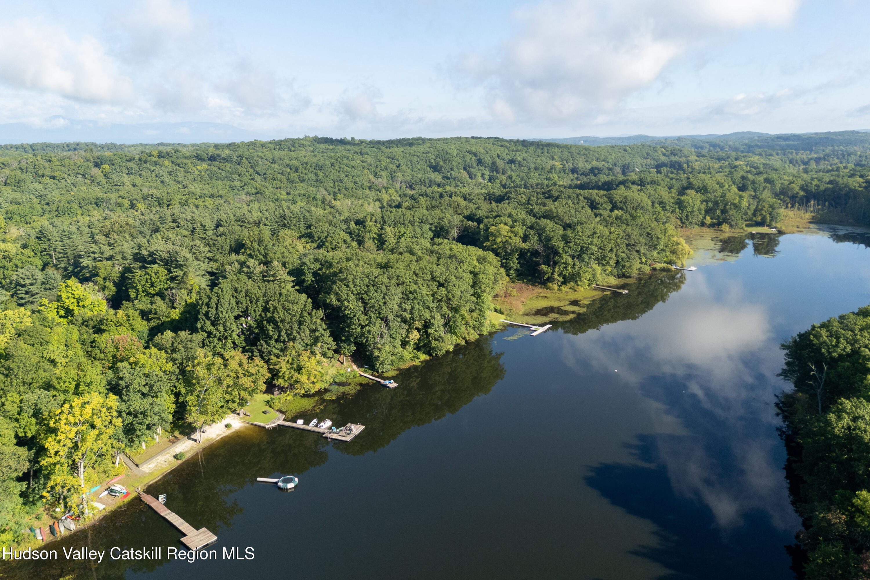 Aerial view of wooded Sepasco Lake shoreline with docks and boats.
