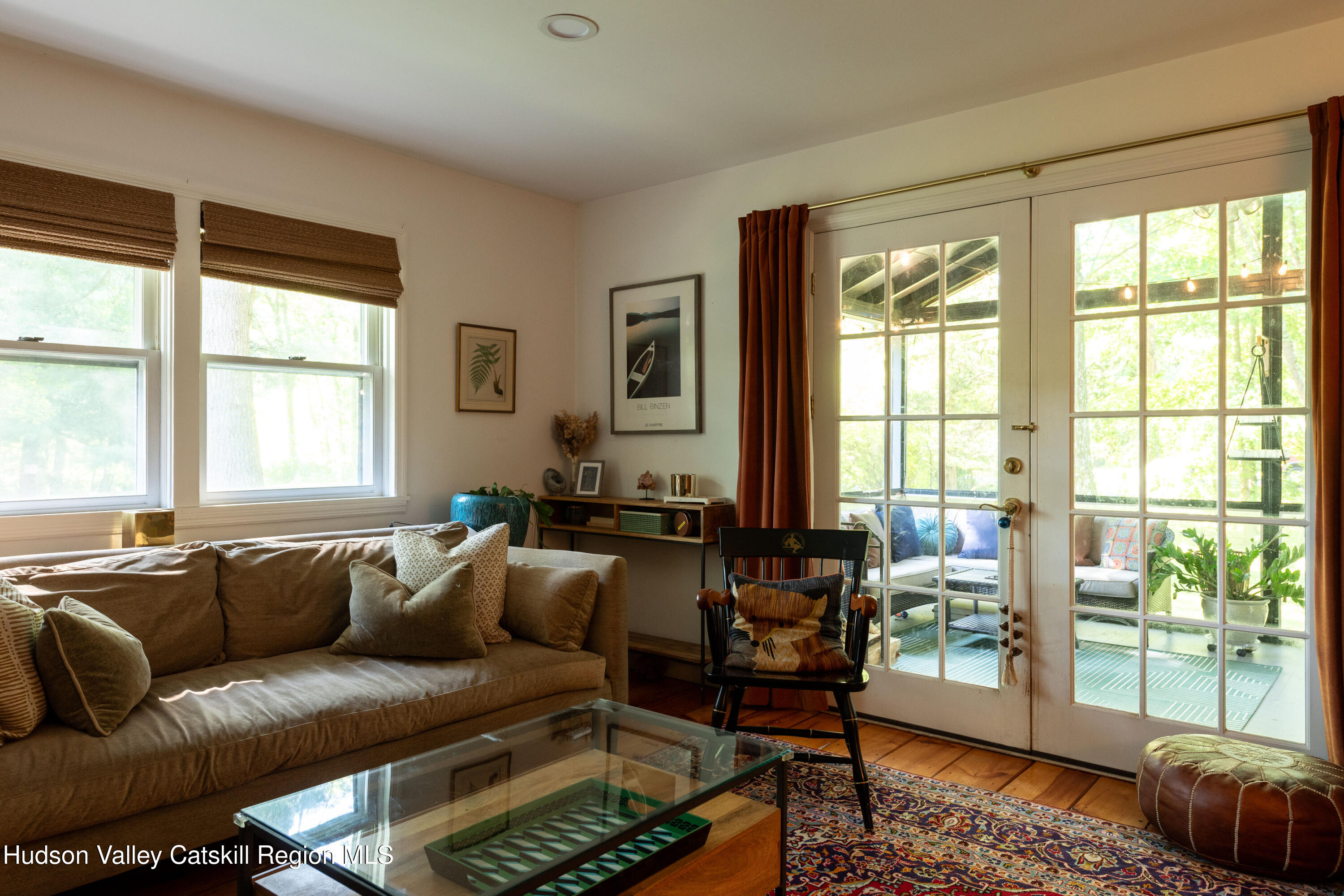 Living room with a tan sofa and French doors opening onto a sunny patio.