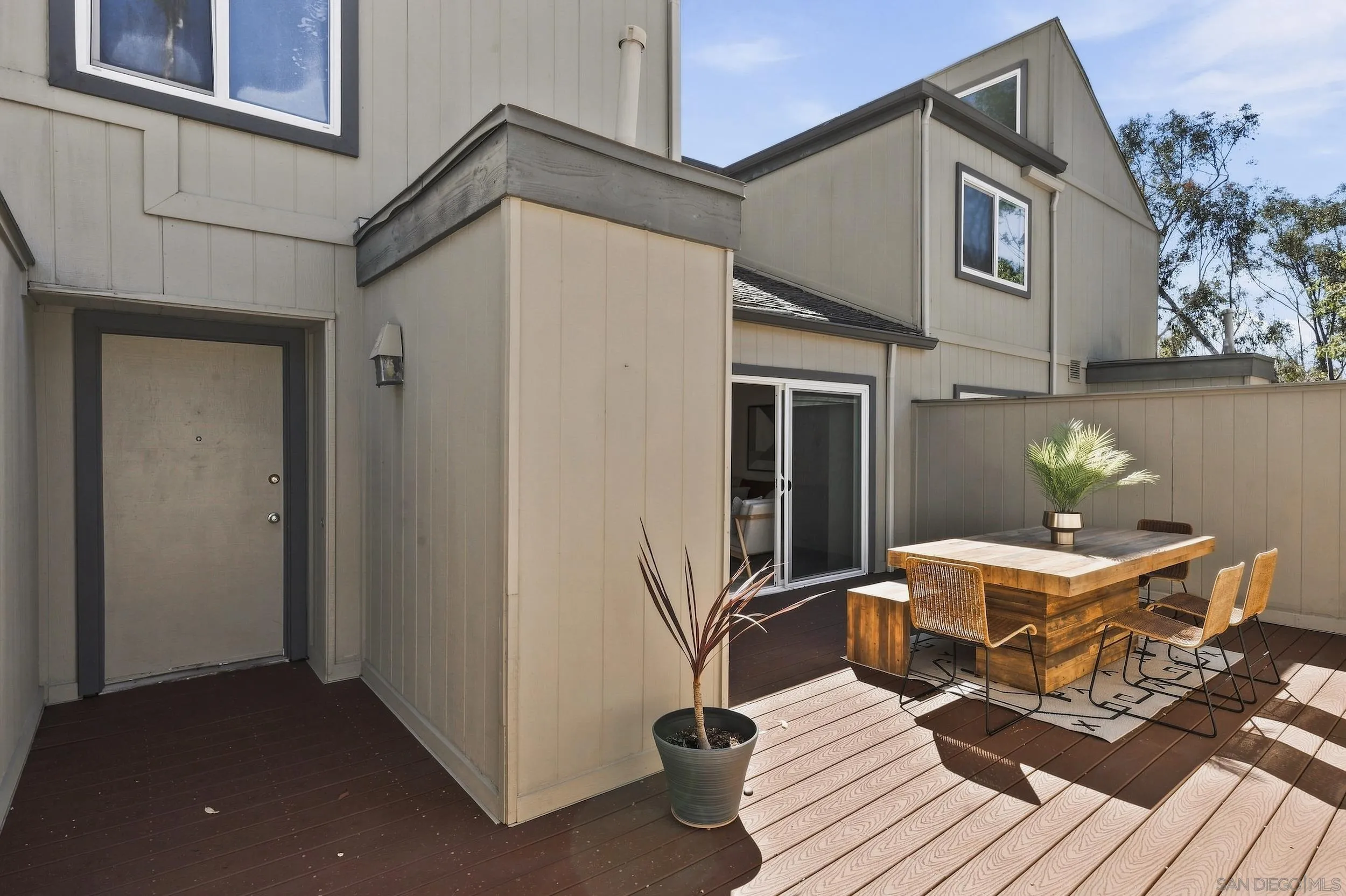 Two-story home exterior with a raised wood deck furnished with an outdoor dining table and chairs.