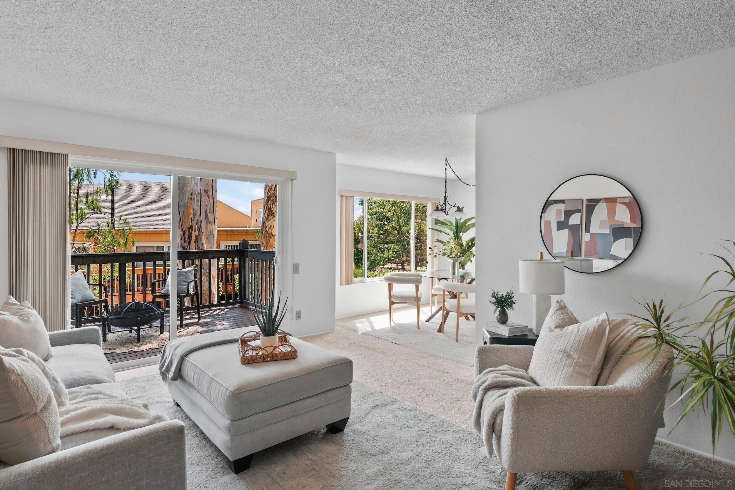Living room with neutral seating, a sunlit dining area, and sliding doors to a balcony.
