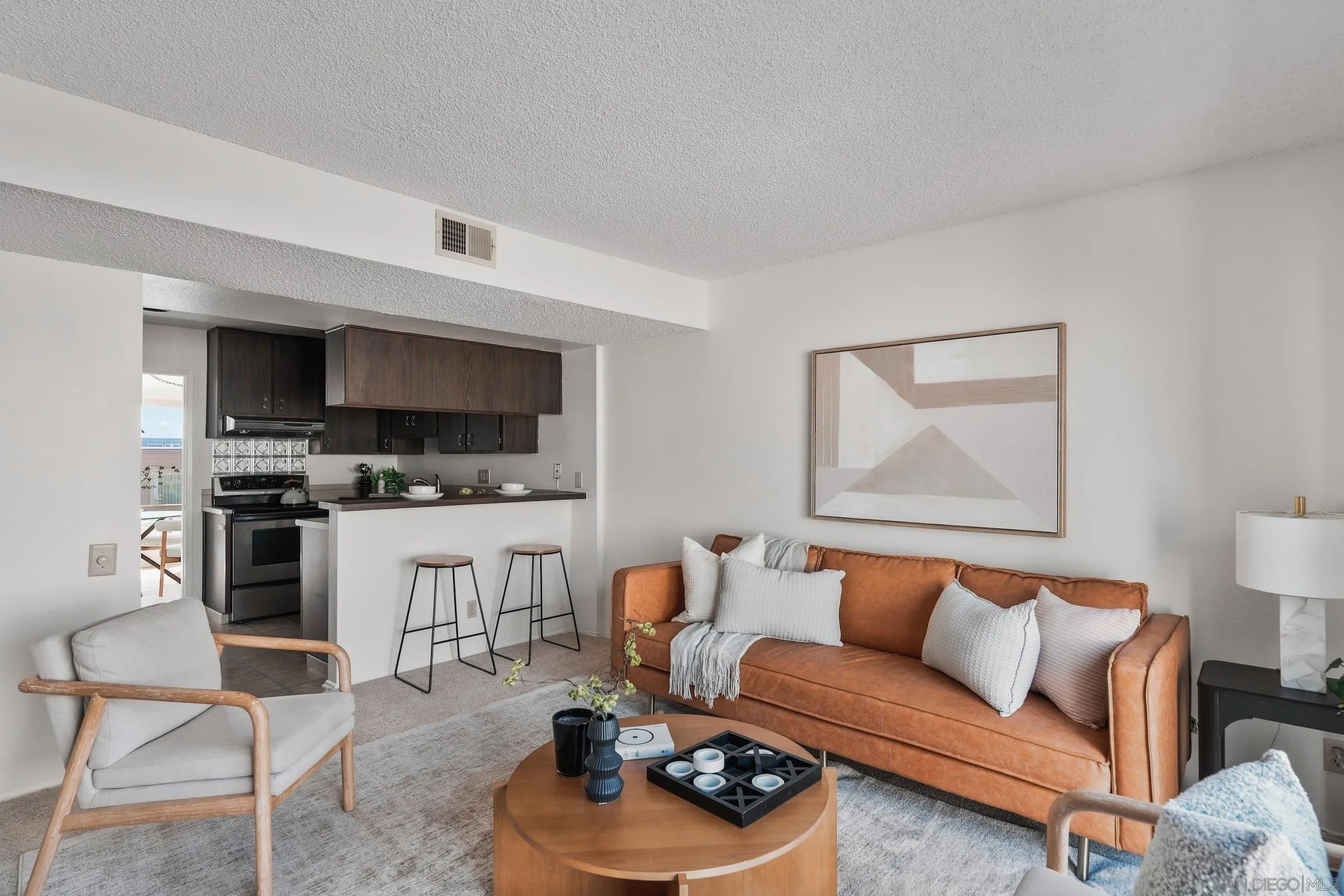 Open-plan living room and kitchen with a rust-colored sofa and breakfast bar.