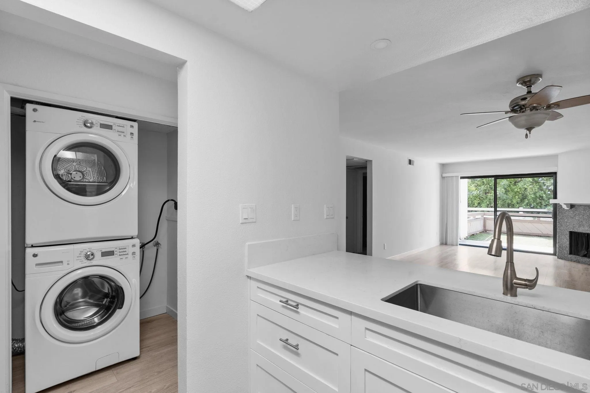 Open kitchen and living area with stacked laundry appliances and sliding doors to a deck.