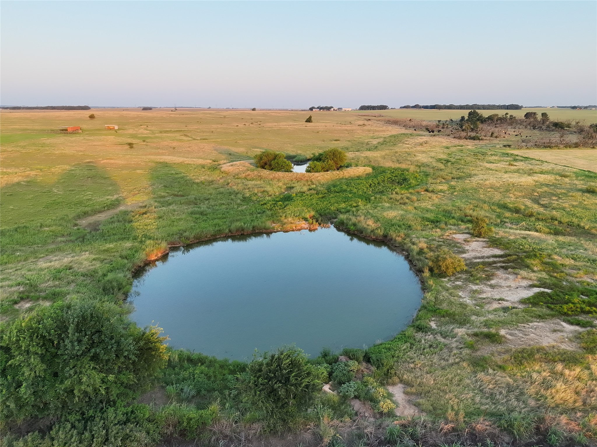 Aerial view of grassy pasture with a large pond in the foreground and a smaller pond beyond.