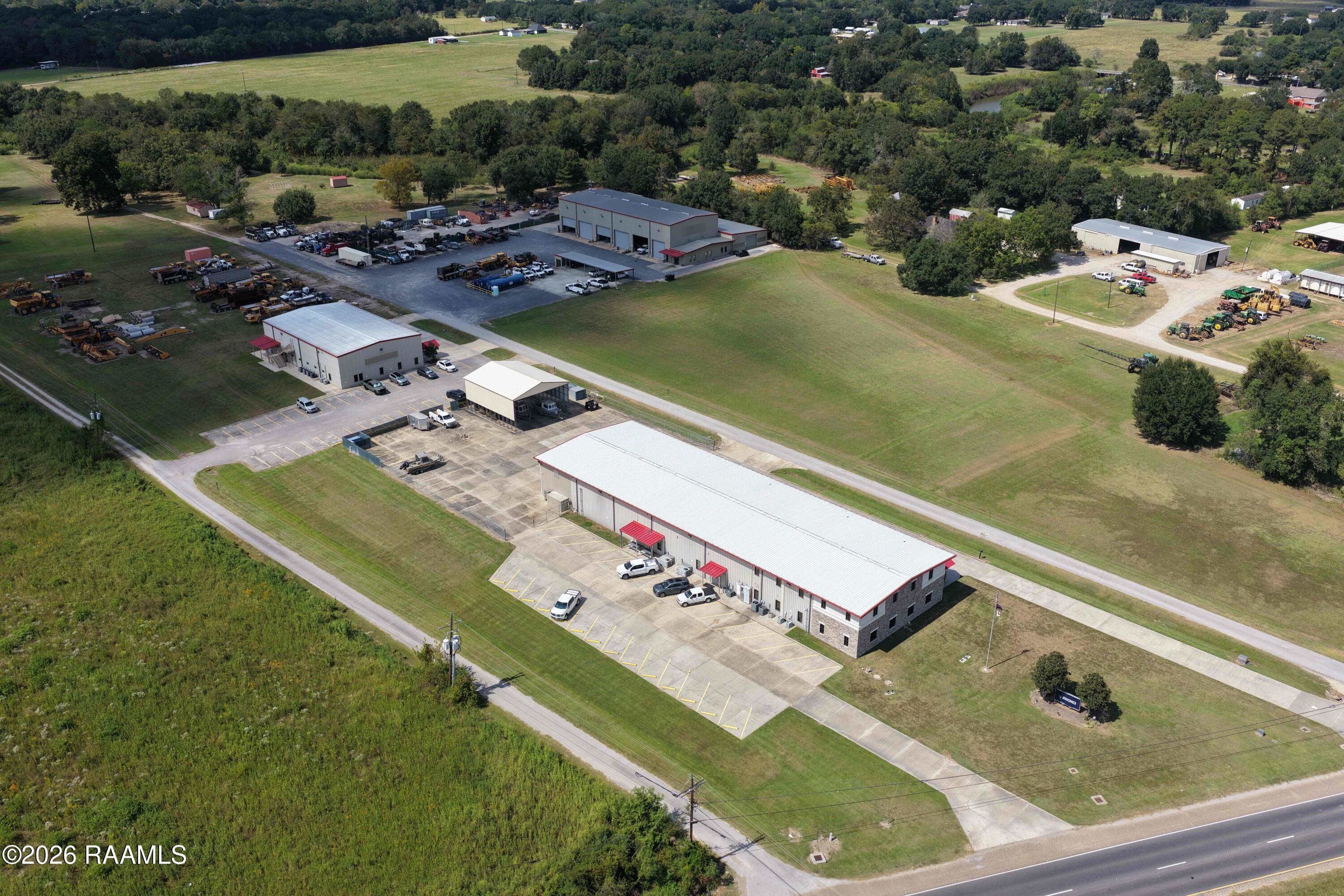 Aerial view of commercial buildings with equipment yards and parking areas.
