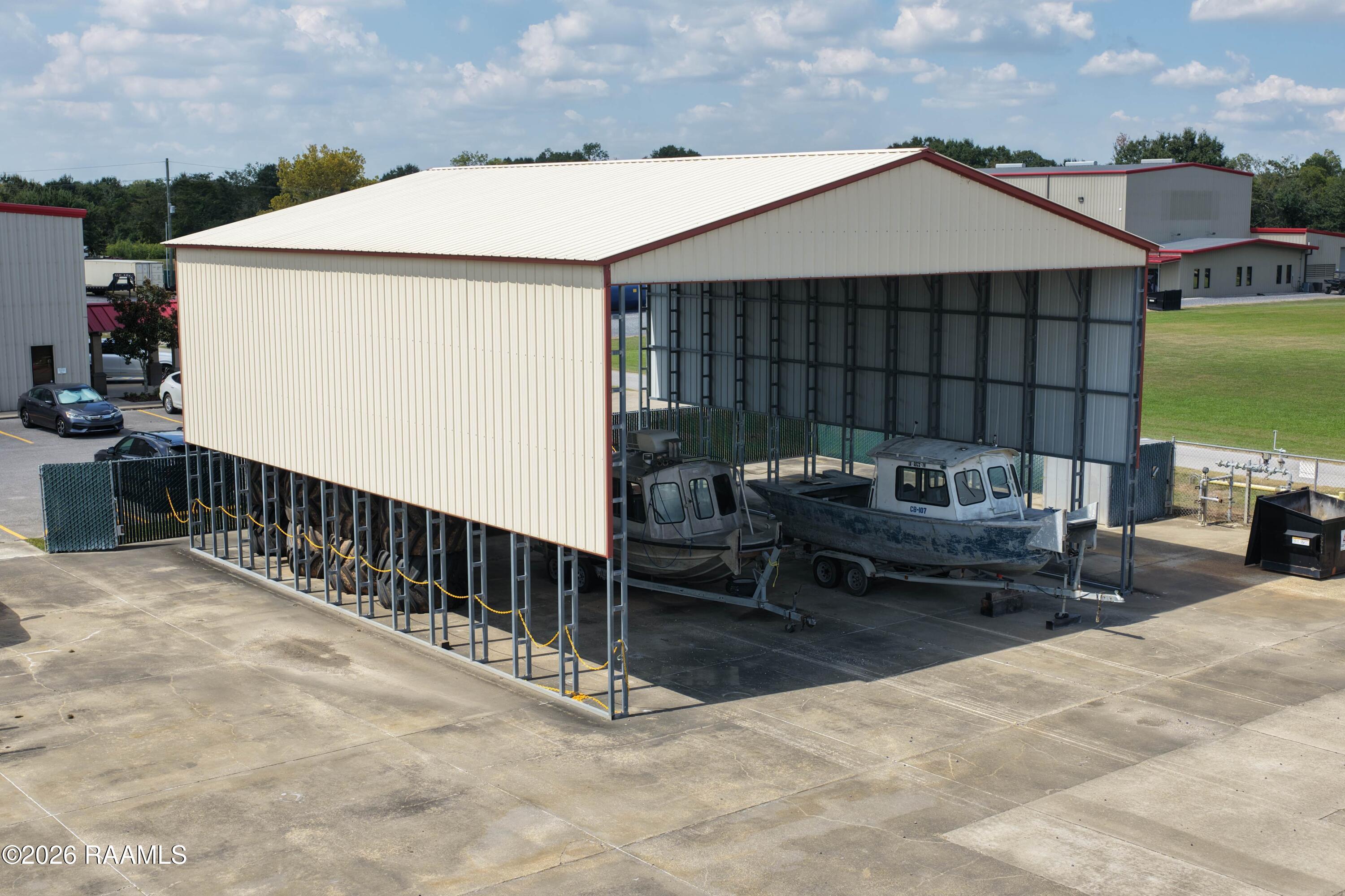 Metal boat-storage building with boats parked beneath its open-sided roof on a concrete lot.
