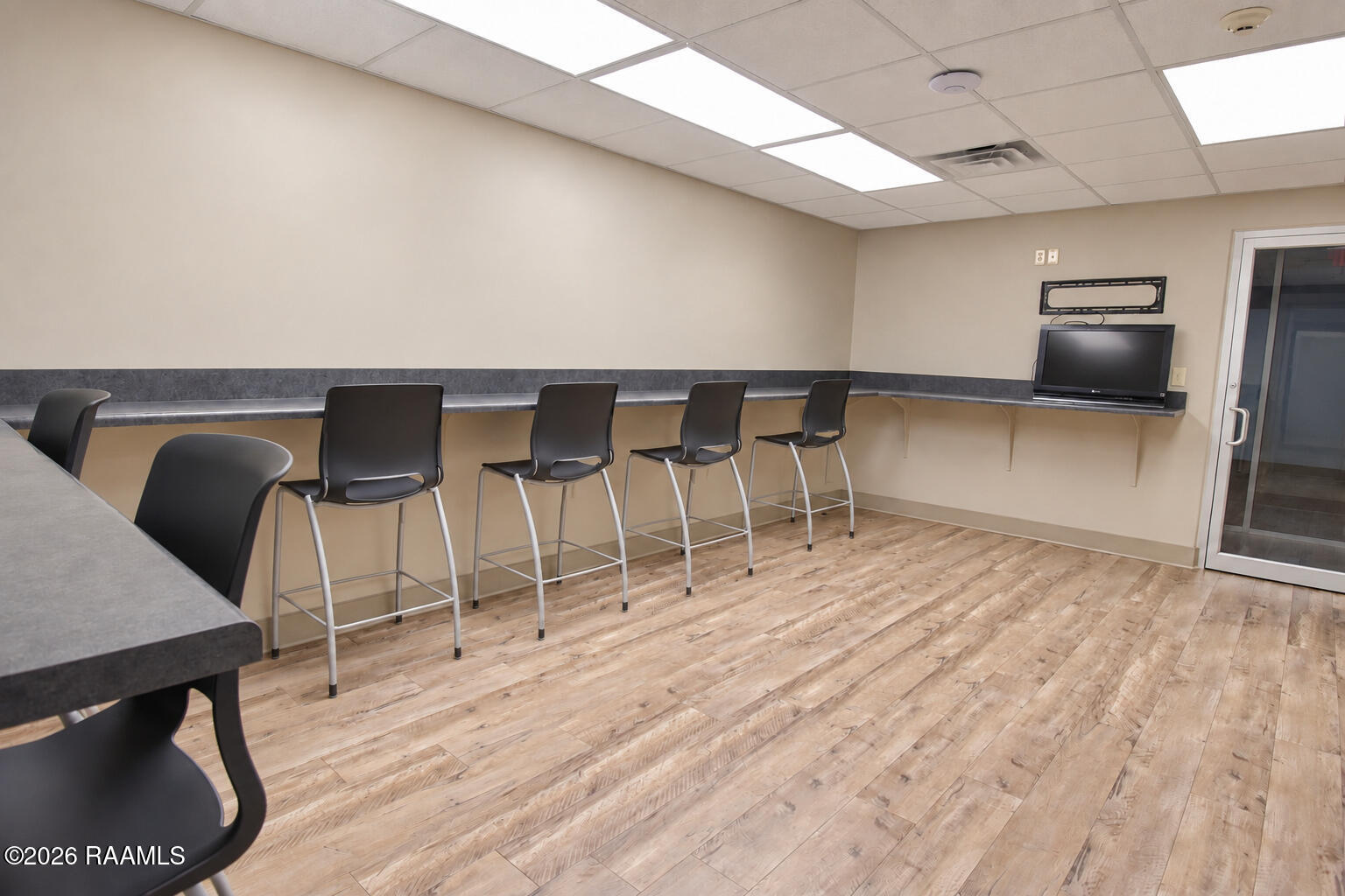 Interior counter seating area with black bar-height chairs and wood-look flooring.