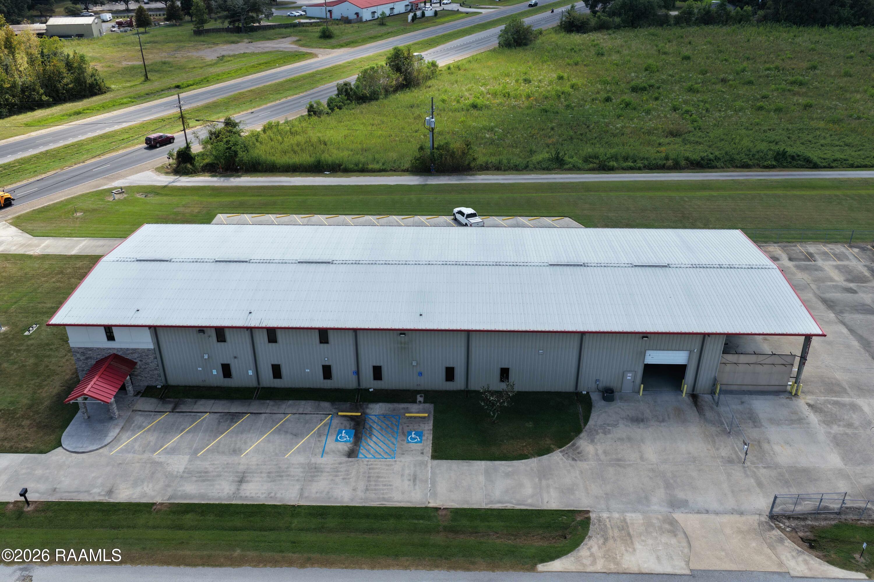 Aerial view of a commercial warehouse with a broad white roof, accessible parking, and a loading bay.