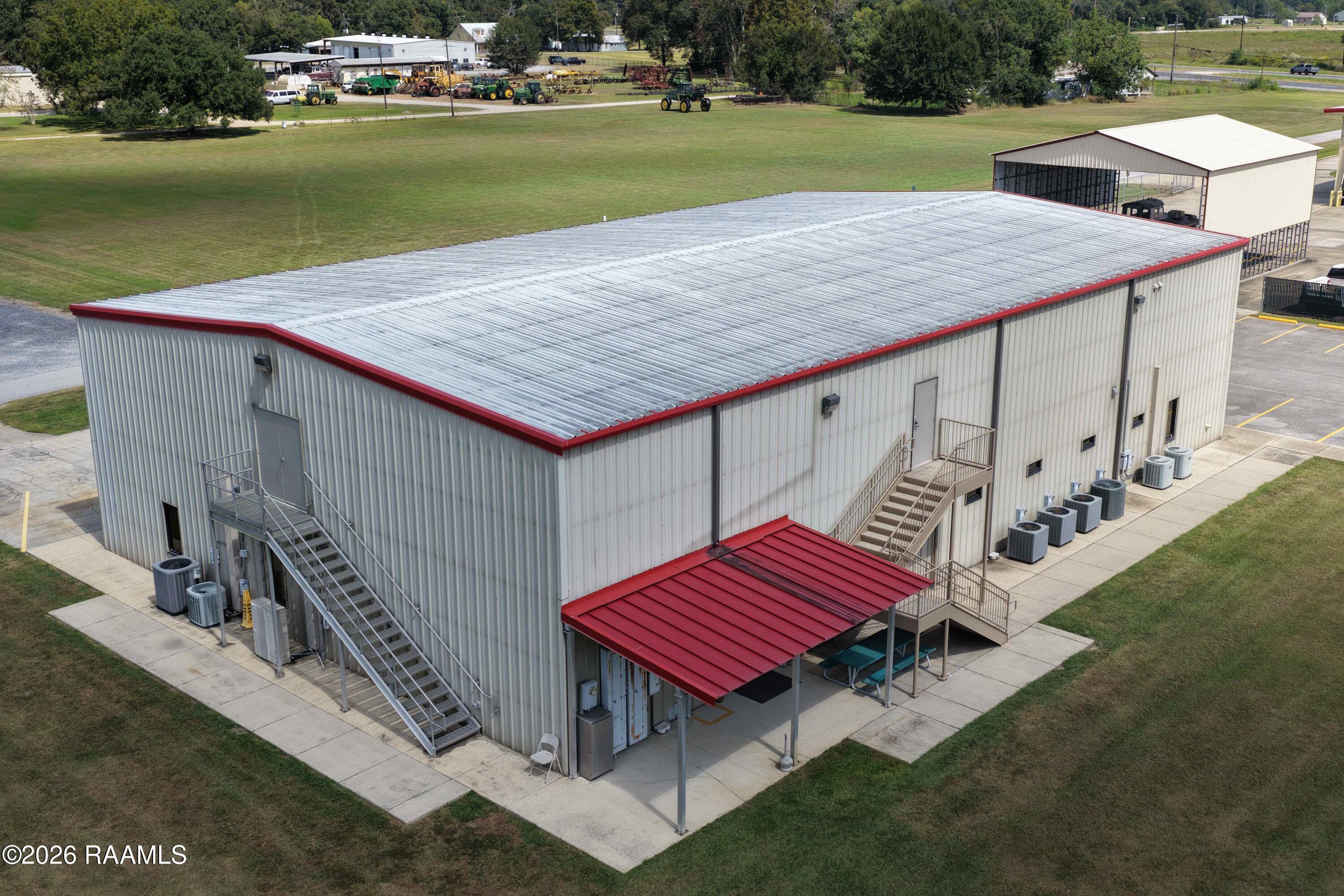 Commercial metal building with red roof trim, exterior stairs, and a covered entrance.