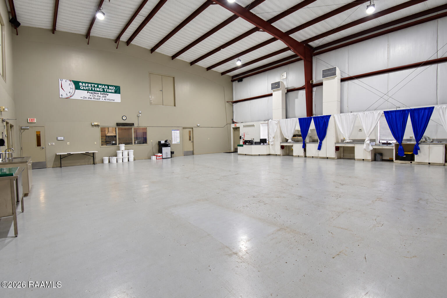 Large commercial interior with an open floor, exposed steel trusses, and curtained service counters.