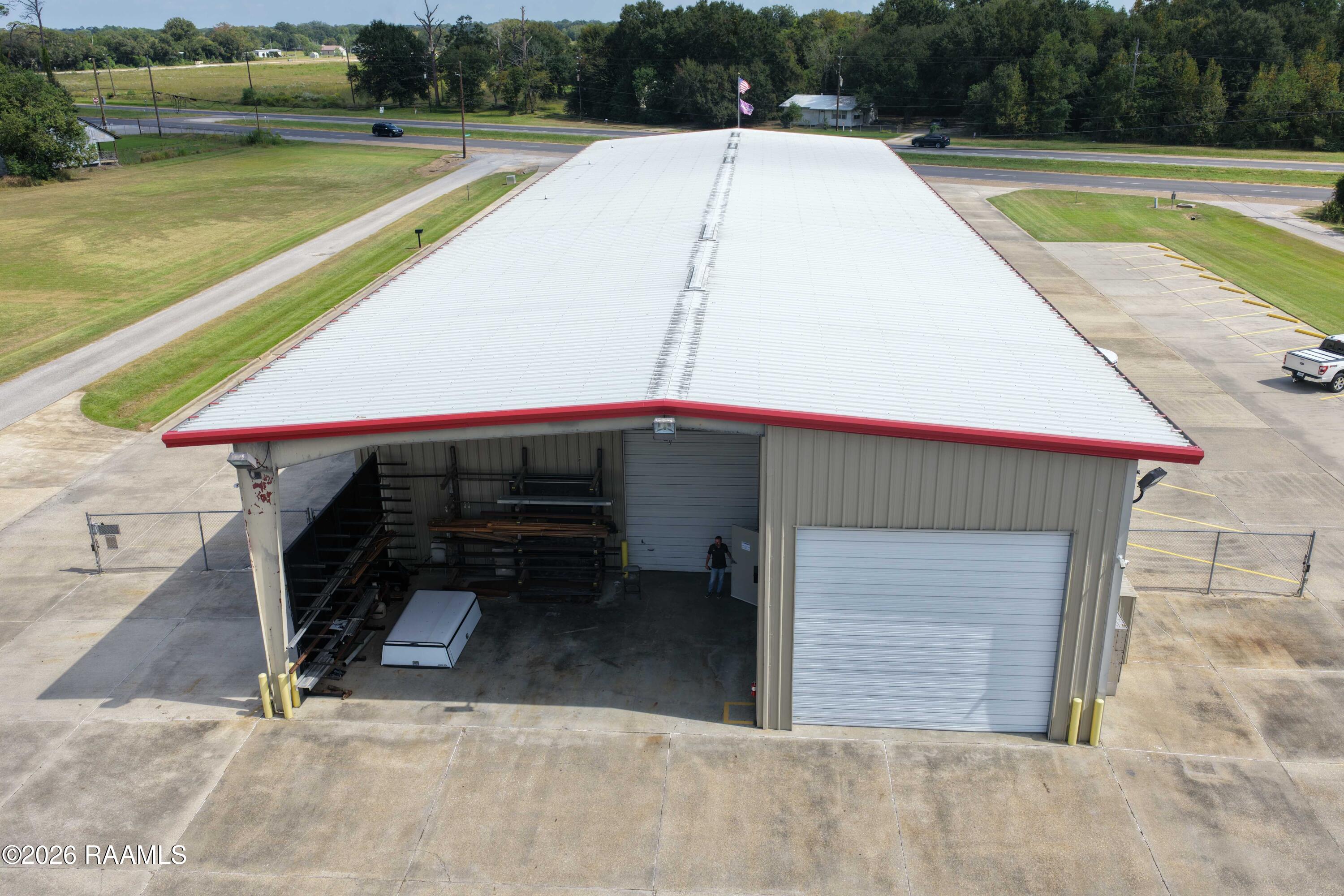 Metal commercial warehouse with red roof trim, an open storage bay, and a closed roll-up door.