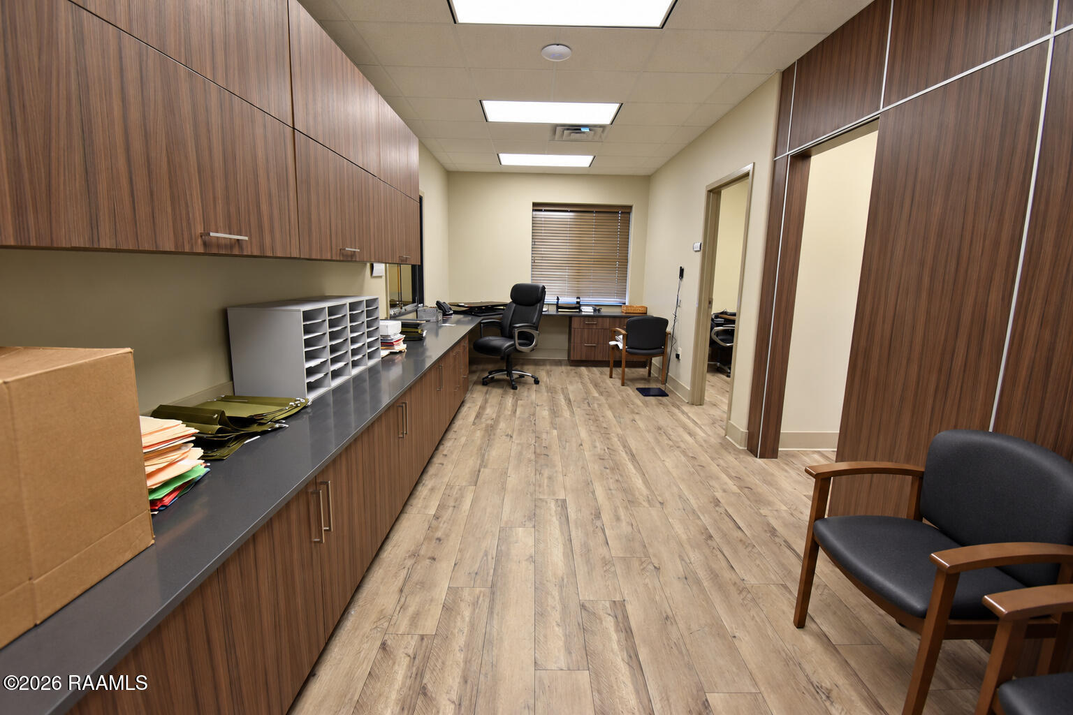 Office interior with wood cabinetry, plank flooring, a desk, and several chairs.