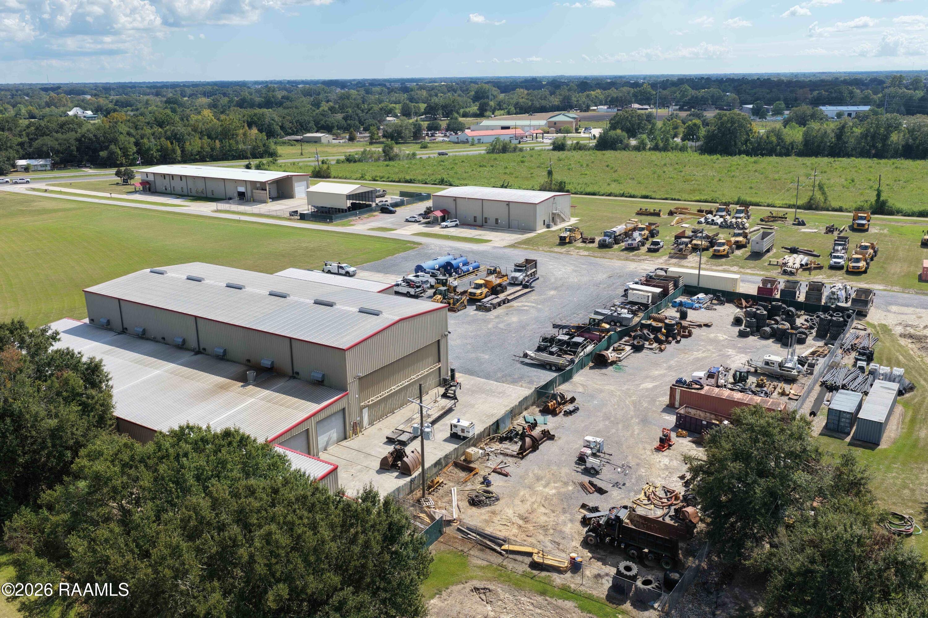 Aerial view of an industrial property with metal warehouses and yards filled with heavy equipment.