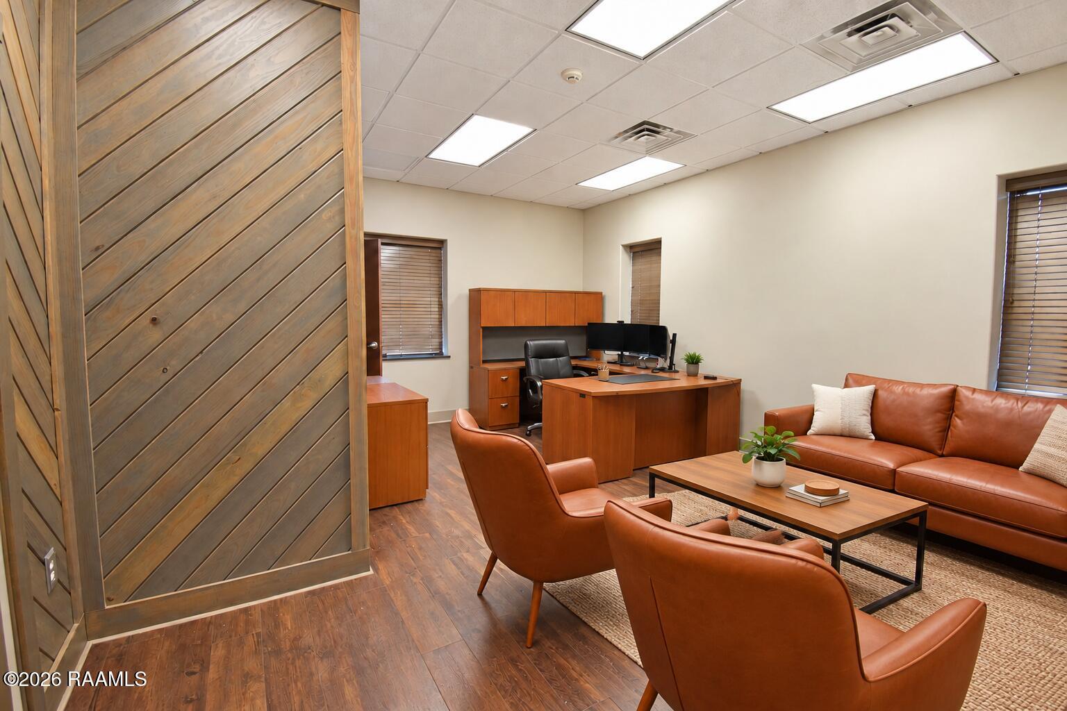 Furnished office with a wood-paneled partition, desk, and brown leather seating area.