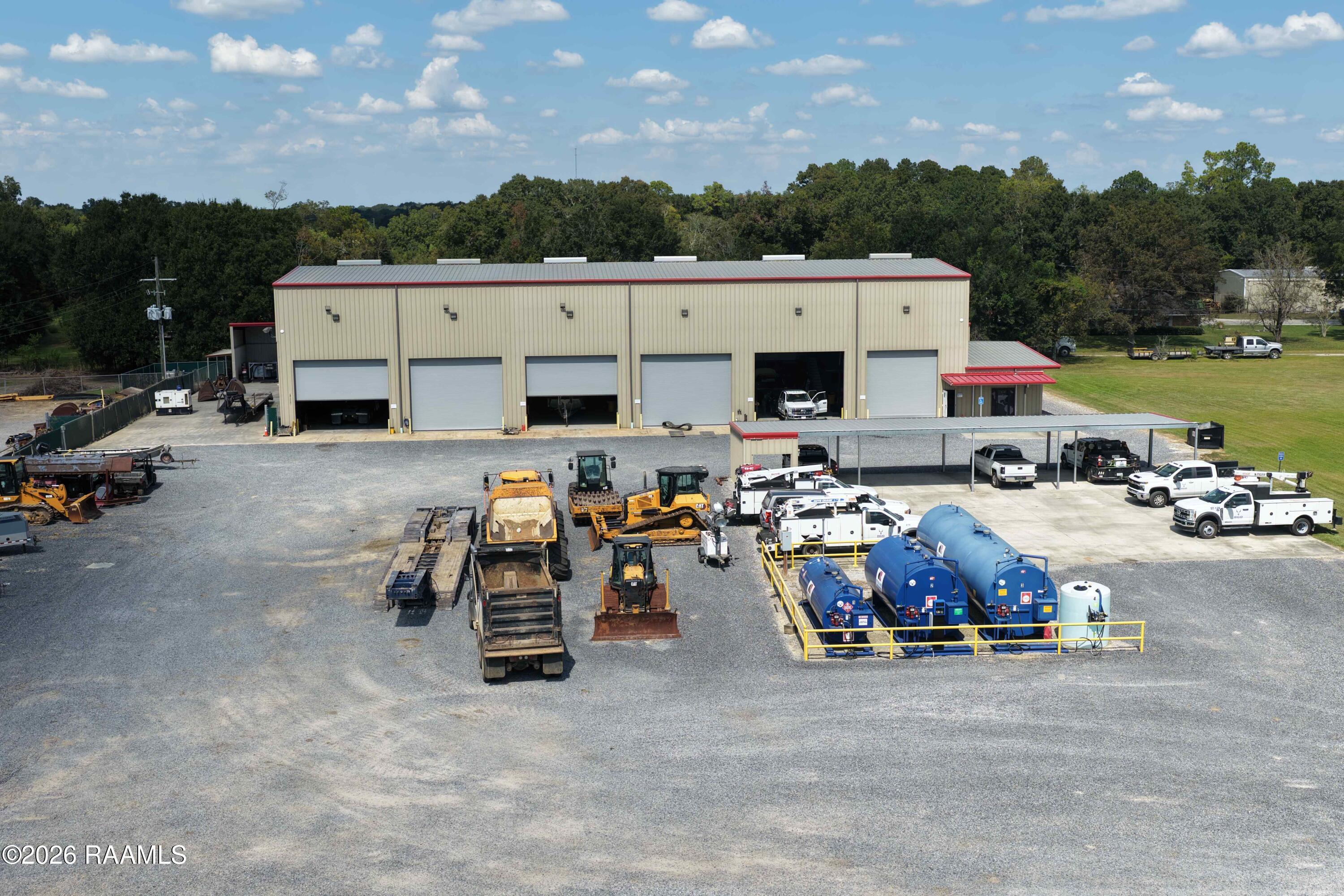Aerial view of a commercial equipment facility with service bays, work trucks, and heavy machinery.