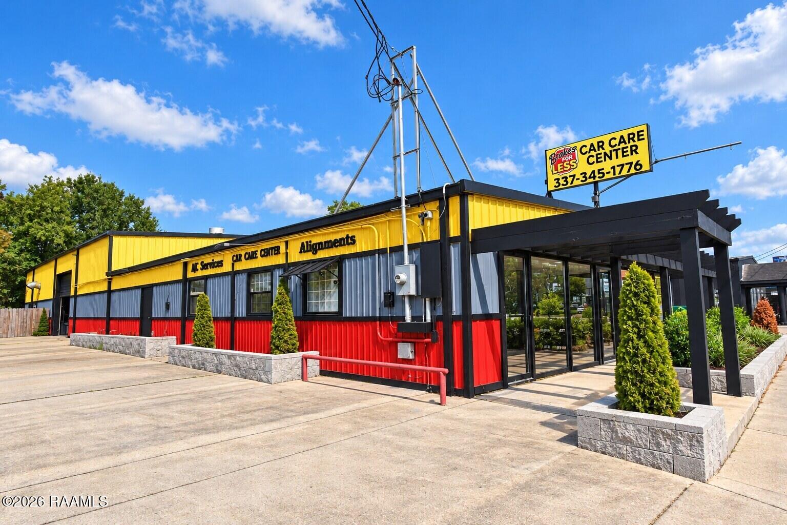 Car care center with a yellow, gray, and red facade and a prominent Brakes for Less sign.