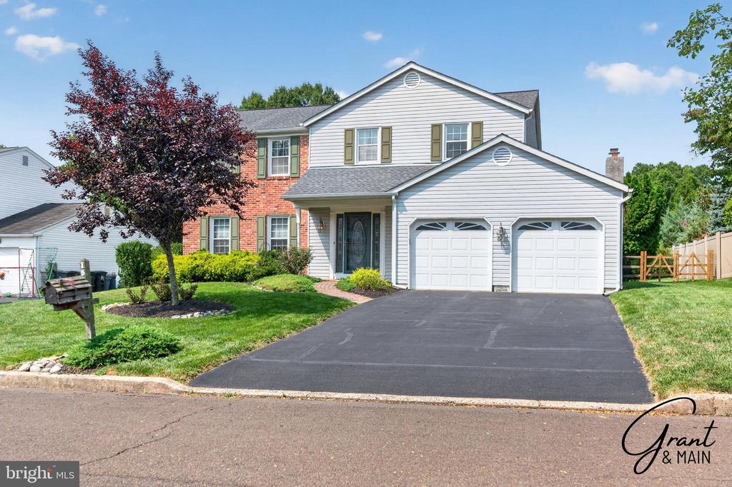 Two-story home with white siding, red brick, a double garage, and a wide paved driveway.