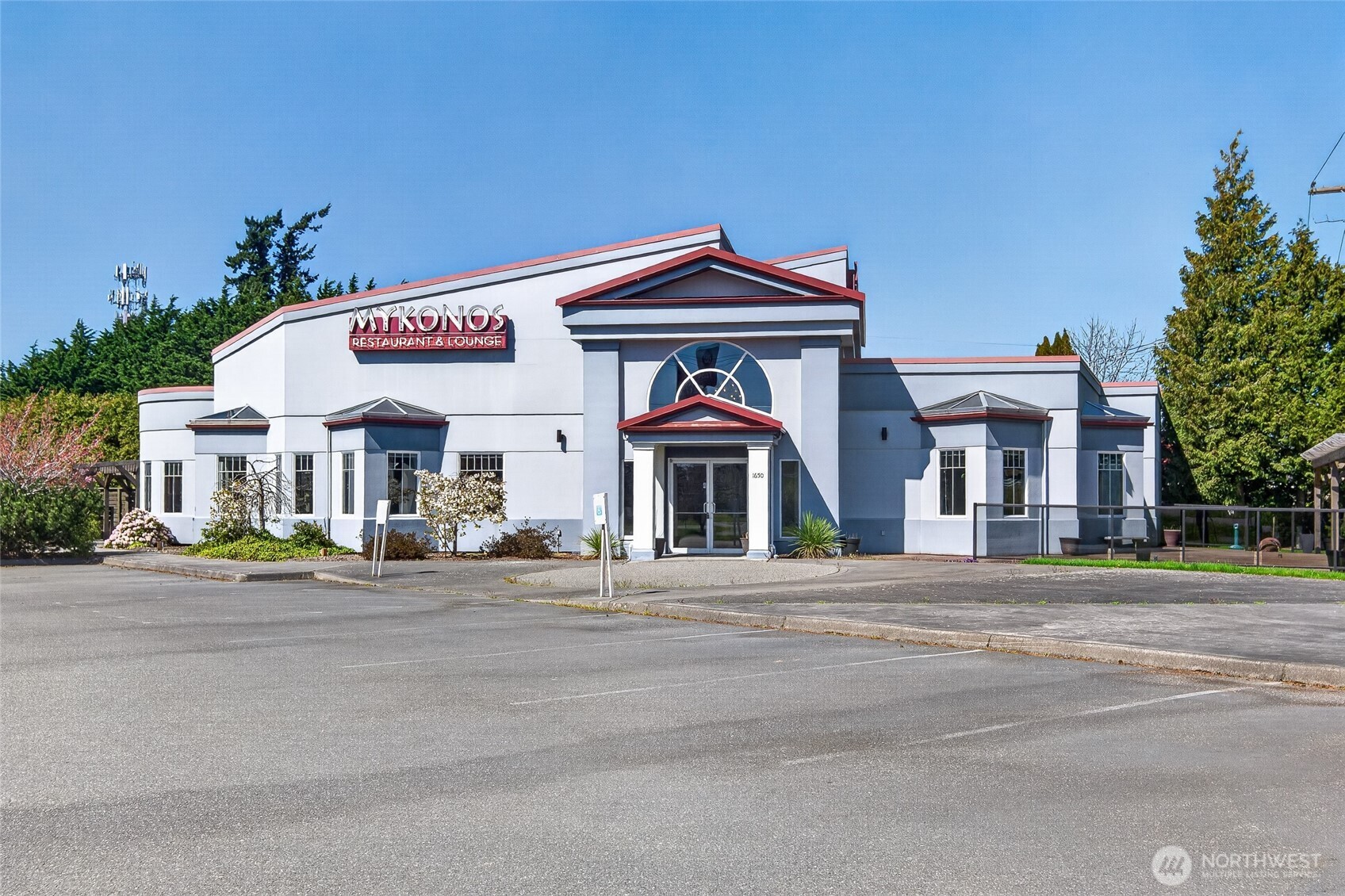 Commercial building with red roof trim, arched entrance window, and Mykonos Restaurant & Lounge sign.