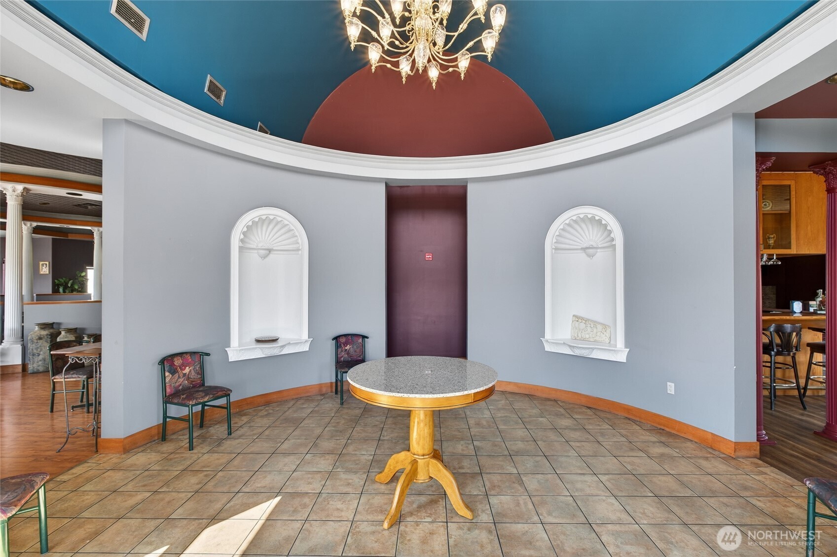 Furnished interior with a round table beneath a blue domed ceiling and chandelier.