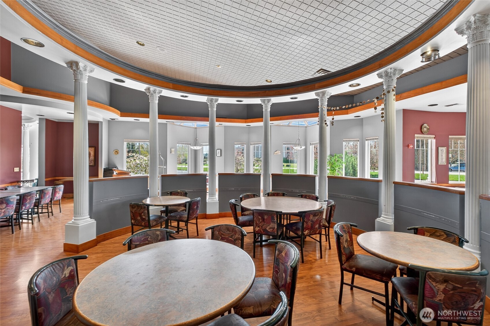 Commercial dining room with round tables, ornate columns, and a patterned ceiling.