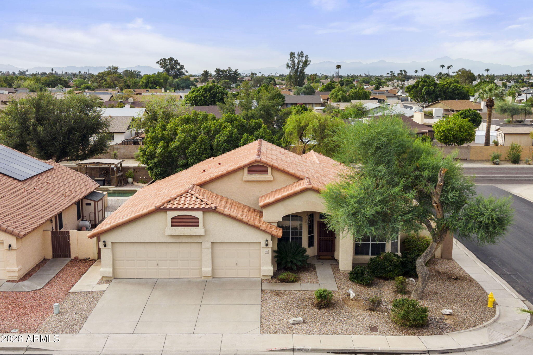 Single-story stucco home with a tile roof and desert landscaping, with Glendale homes and mountains in the distance.