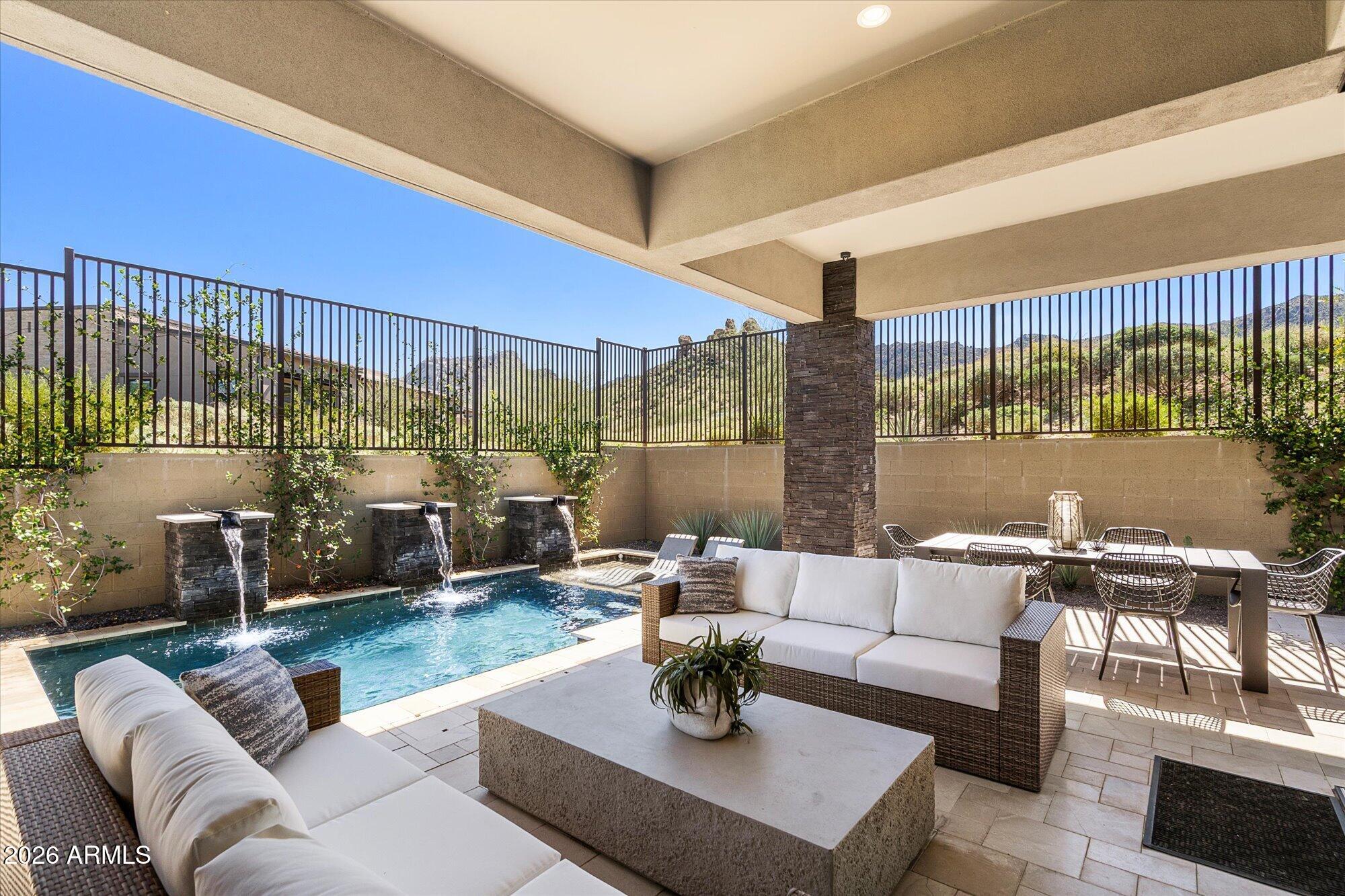 Covered patio with a pool, wicker seating, dining area, and distant mountain views.