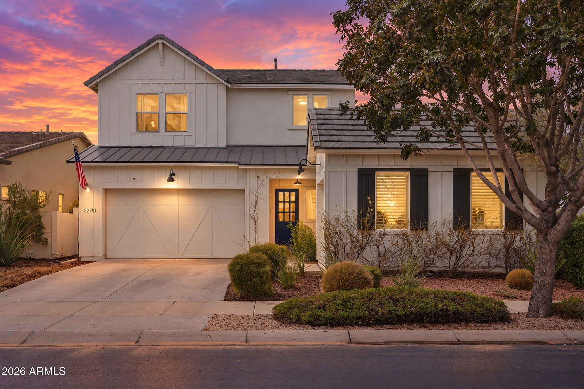 Two-story house with a garage and desert landscaping beneath a vivid pink-orange sunset.