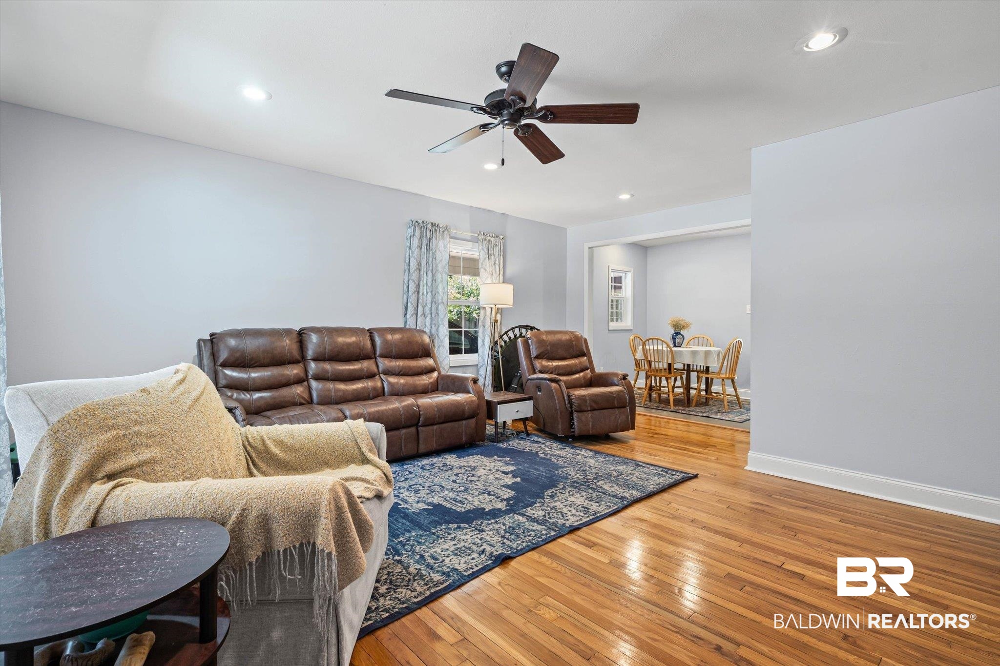 Living room with brown leather recliners, hardwood floors, and an adjoining dining area.